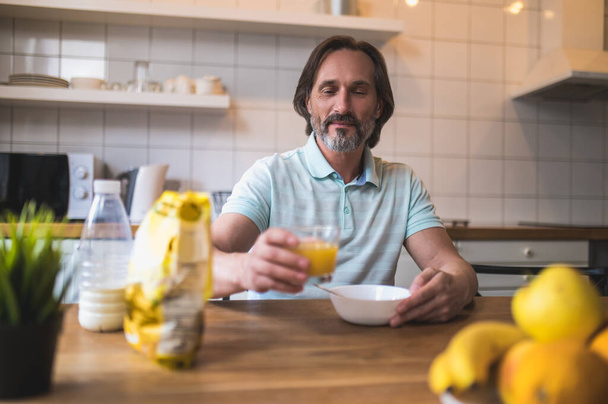 Breakfast. Mature caucasian man sitting at the table and eating breakfast - Фото, зображення