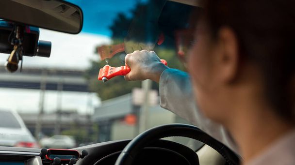 Woman use Safety Hammer and Seatbelt Cutter in Cars, break glass When emergency. In case of emergency on car safety red hammers to break the grass window. - Foto, Imagen