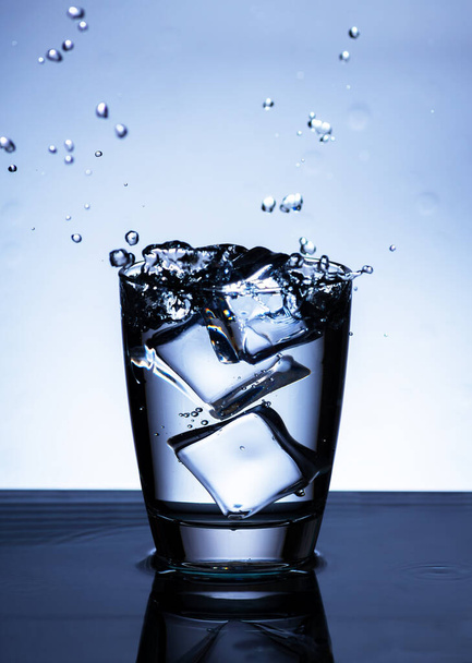 Het beeld van het gieten van drinkwater, in een glas, dat maakt dat men zich verfrist op wazig witte achtergrond, Spetterend water, Sprankelend water - Foto, afbeelding