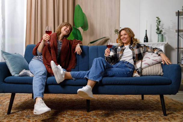 Mutter und Tochter tratschen und trinken zu Hause Wein. Sie sind nicht nur Mutter und Tochter, sondern beste Freunde - Foto, Bild