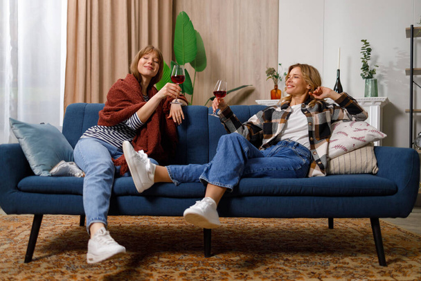 Anya és lánya pihennek a kanapén, miközben bort isznak. - Fotó, kép