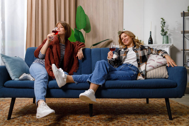 Γυναίκα και η κόρη της πίνουν κρασί και διασκεδάζουν στο σπίτι. - Φωτογραφία, εικόνα