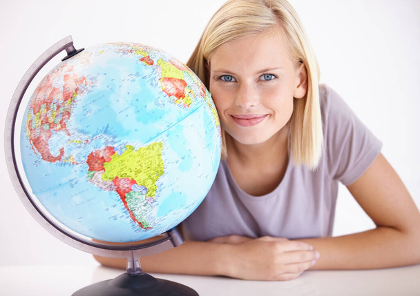 География ее специальность. Красивая молодая учительница географии, улыбающаяся рядом с земным шаром - Фото, изображение