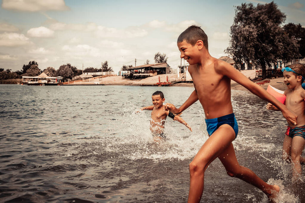 Carefree boys having fun in summer day while running through the sea.  - Photo, Image