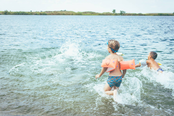 Kleine kinderen krijgen in het water en plezier tijdens het zwemmen op zomervakantie.  - Foto, afbeelding