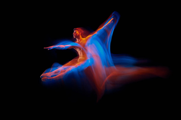 Aspiracja. Solowy występ giętkiego tancerza baletowego odizolowanego na ciemnym tle w jaskrawym, neonowym świetle. Grace, sztuka, piękno, kontemplacja tańca. Aktor latający, skaczący - Zdjęcie, obraz