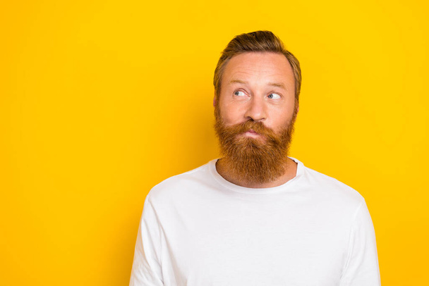 Photo of young bearded handsome guy redhair thoughtful minded look empty space interesting deal offer ad isolated on yellow color background. - Фото, зображення