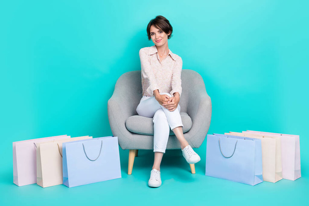 Photo of pretty adorable lady wear trendy clothes outfit sit cozy chair fitting room satisfied purchase isolated on cyan color background. - Foto, afbeelding