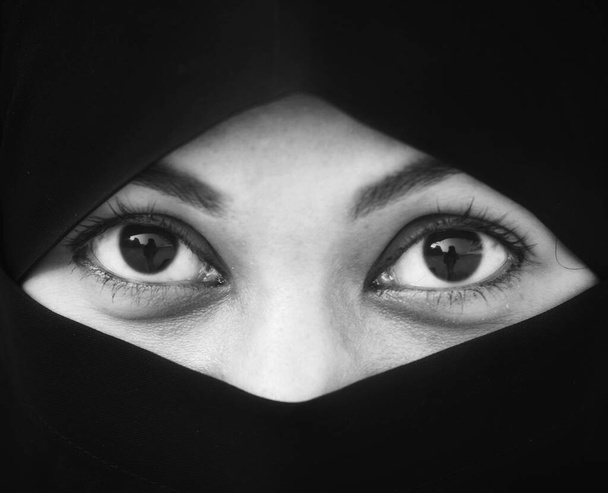 Крупный план красивой женщины, покрытой хиджабом. Идеальные блестящие глаза мусульманской девушки. Портрет девушки-никаба на заднем плане. - Фото, изображение