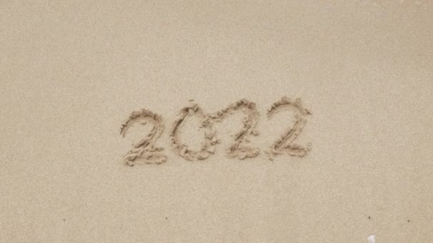2022 χέρι γράψει στοιχεία για την αμμώδη παραλία για Ευτυχισμένο το Νέο Έτος 2023, το κύμα της θάλασσας ξεπλένει τον αριθμό χέρι γραμμένο στη χρυσή άμμο παραλία θάλασσα. Αντίο 2022 - Πλάνα, βίντεο