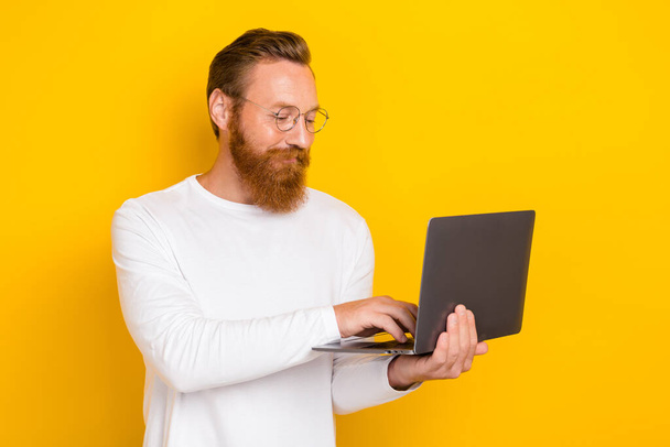 Portrait of positive intelligent person hold use wireless netbook networking isolated on yellow color background. - Photo, Image