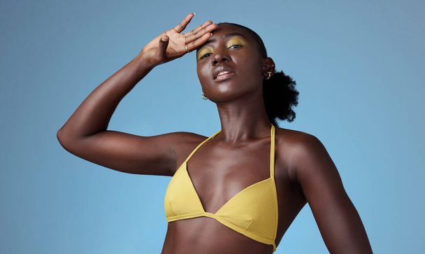 Black beauty, yellow bikini and an African woman on blue background, sexy in yellow. Bright makeup, dark skin and a beautiful girl. Skincare, colorful cosmetics and a portrait of lady from Africa - Photo, Image