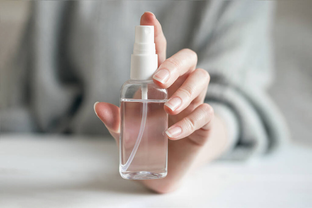 Жіноча рука тримає пляшку гелю для дезінфікування, антибактеріальний спиртний спрей від бактерій коронавірусу, ізольованих на синьому фоні, ковадло 19, гігієна рук
 - Фото, зображення