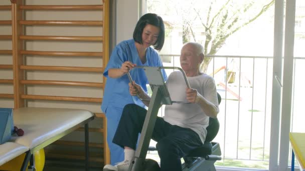 Idős férfi a tornateremben, ázsiai edző támogatásával. - Felvétel, videó