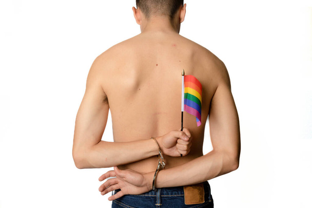 A Shirtless 19 Year Old Teenage Boy with Pride Flags in Handcuffs - 写真・画像