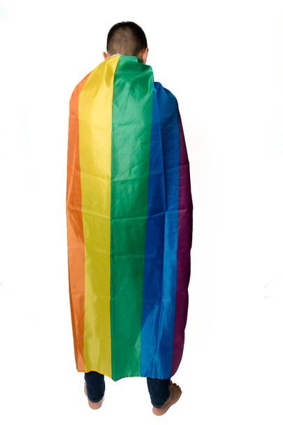 A Shirtless 19 Year Old Teenage Boy wrapped in A Pride Flag - 写真・画像