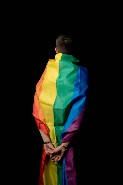 A Shirtless 19 Year Old Teenage Boy wrapped in A Pride Flag Under Arrest From Behind - Foto, imagen