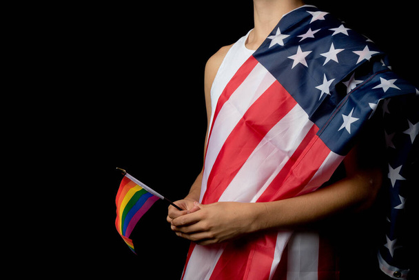 A portrait of a nineteen year old teen boy on a black background with an American Flag and white board and Pride Flags - Foto, imagen