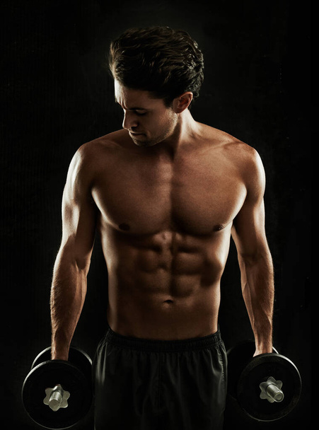 Ready to beast a workout. Built young man holding his dumbbells to his sides, ready for a workout - Foto, afbeelding
