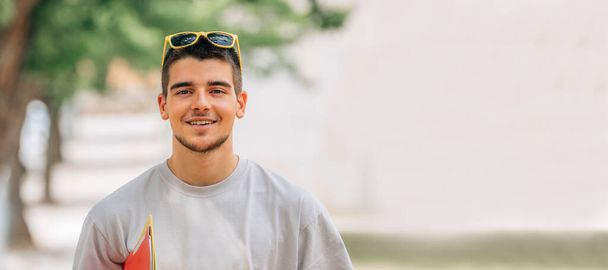 улыбающийся студент в кампусе или колледже на открытом воздухе - Фото, изображение