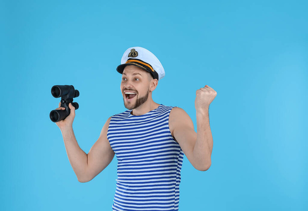 Happy sailor with binoculars on light blue background - Фото, изображение