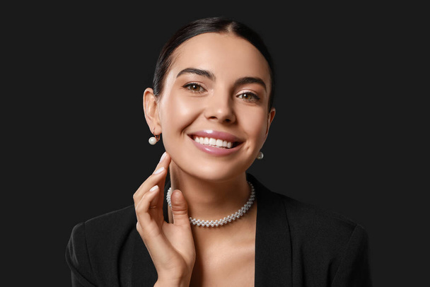 Young woman with elegant pearl jewelry on black background - Photo, image