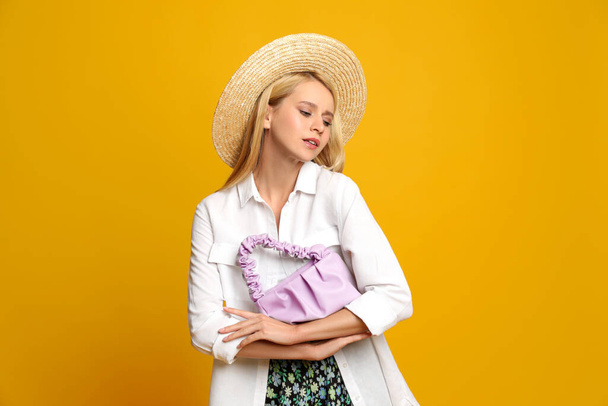Beautiful stylish woman with trendy baguette bag on yellow background - Fotó, kép