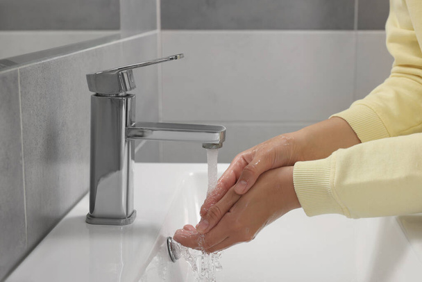 Woman washing hands with water from tap in bathroom, closeup - Foto, imagen