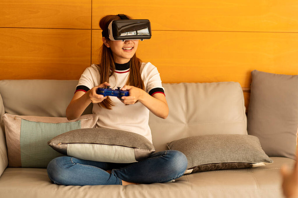 Aasialainen nainen yllään 3D VR lasit hymyilevä ja hauskaa olohuoneessa kotona Virtuaalisia käsitteitä ja pelaamista metaverses - Valokuva, kuva