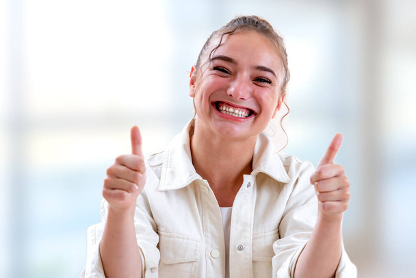 Horizontal shot of a Woman expressing her joy by keeping her thumbs up - Fotó, kép