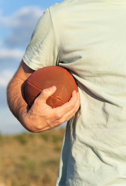 Vertical view of a male hand holding a rugby ball. - Fotó, kép