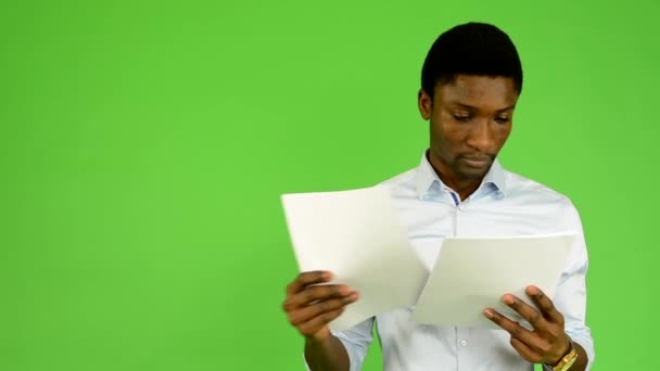 Młody przystojny czarny człowiek czyta dokumenty - zielony ekran - studio - Materiał filmowy, wideo