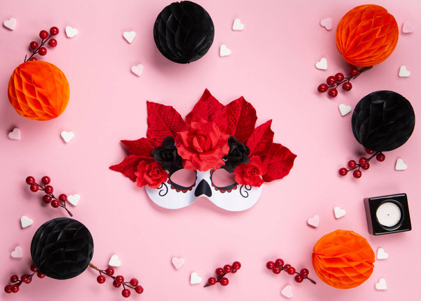 Dia de los Muertos, mexikanischer Feiertag der Toten und Halloween. Weiße Karneval Catarina Maske, Kerzen, Blumen und mexikanische Objekte auf rosa Hintergrund. Konzeptplakat, Banner, Festkarte. - Foto, Bild