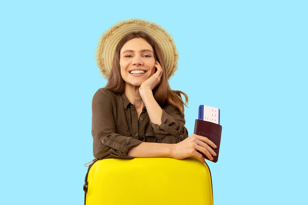 Neşeli turist kadın pasaport ve seyahat biletleriyle poz veriyor Mavi Stüdyo arka planında oturan kameraya gülümsüyor. Büyük Tatil Teklifi, Tatil Konsepti - Fotoğraf, Görsel