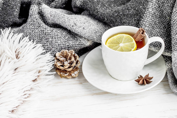Beyaz ahşap arka planda limonlu ve tarçınlı bir fincan çay. - Fotoğraf, Görsel
