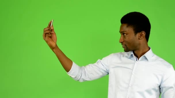Young handsome black man photographs with smartphone (selfie) - green screen - studio - Footage, Video