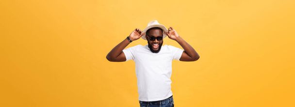 Close up portrait of a young man laughing with hands holding hat isolate over yellow background. - Photo, Image