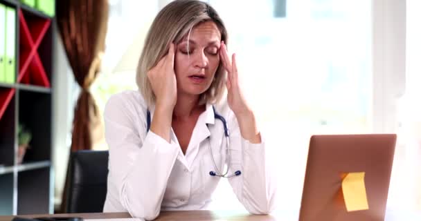 Médico frustrado con dolor de cabeza en la oficina que masajea las sienes. Enfermedad y médico cansado - Imágenes, Vídeo