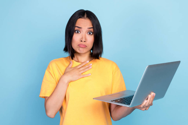Photo of nice cute impressed woman bob hairdo dressed yellow t-shirt hold laptop hand on chest asking isolated on blue color background. - Foto, Imagem