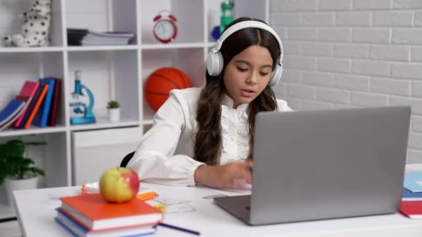 alumna sonriente en uniforme escolar y auriculares que se comunican en la lección de vídeo con el ordenador, la escuela. - Imágenes, Vídeo