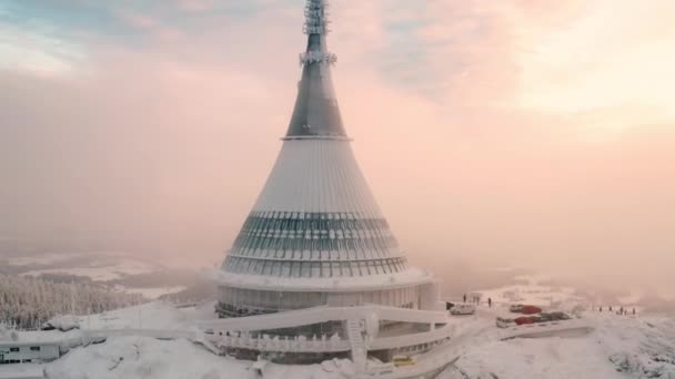 雪に覆われたリベレツの高い山の上に建てられたホテルやレストランとジェストタワー。煙霧の空中ビューで尖塔と未来的な建設 - 映像、動画