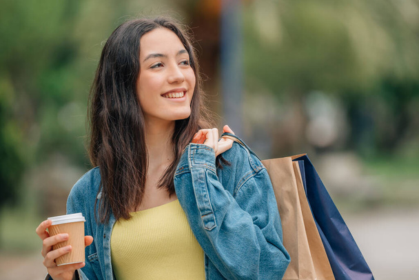 dziewczyna na ulicy handlowej z torbami i filiżanką kawy - Zdjęcie, obraz