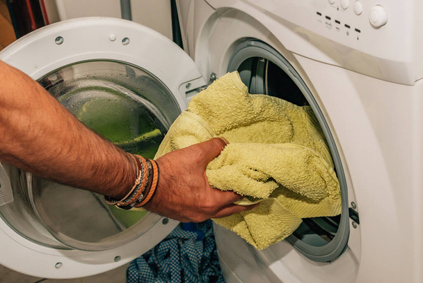 hand putting clothes to wash in the washing machine - 写真・画像
