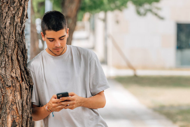молодий чоловік на вулиці з мобільним телефоном або смартфоном
 - Фото, зображення