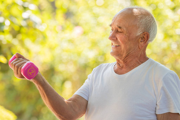 uomo anziano che fa sport o esercizio all'aperto con manubri - Foto, immagini