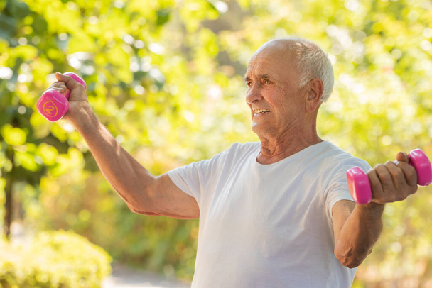 Senioren treiben Sport oder bewegen sich im Freien mit Kurzhanteln - Foto, Bild