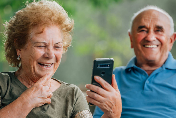 senior couple smiling fun with mobile phone or smartphone - Photo, Image