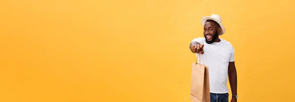African American man with colorful paper bags isolated on yellow background. - Foto, imagen