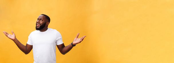 Retrato del hombre afroamericano con las manos levantadas en shock e incredulidad. Aislado sobre fondo amarillo
 - Foto, imagen