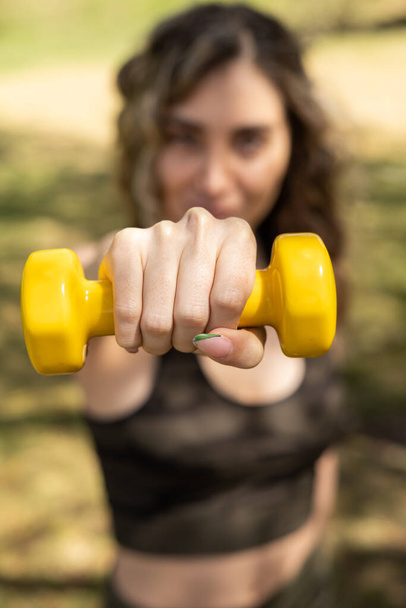 details of a hand holding a yellow dumbbell, fitness training of a young woman, healthy lifestyle with exercise - Fotó, kép